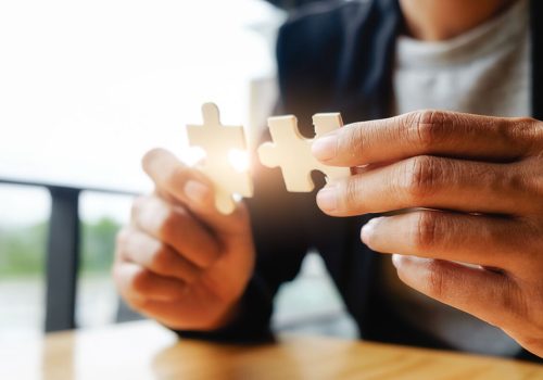 Zwei Puzzleteile in der Hand